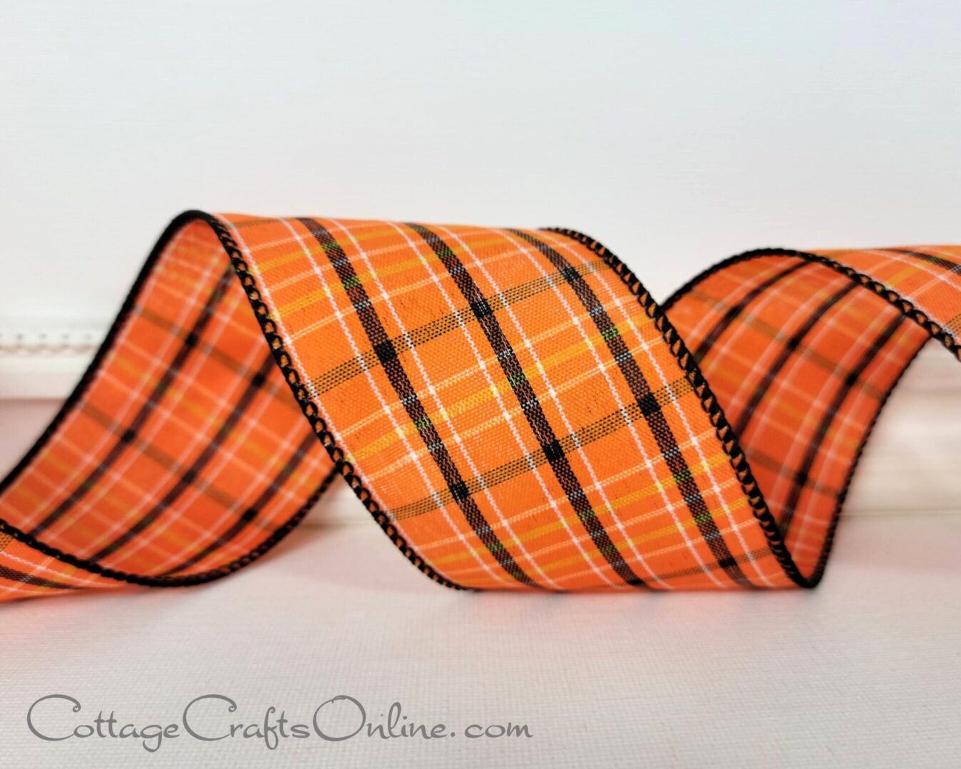 an orange and black plaid ribbon on a white table.