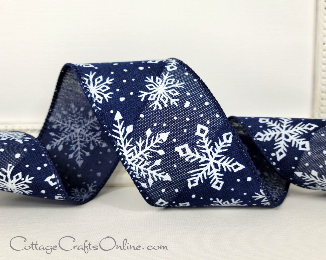 White snowflakes on navy 2.5" wide wired ribbon from the Etsy shop of Cottage Crafts Online.