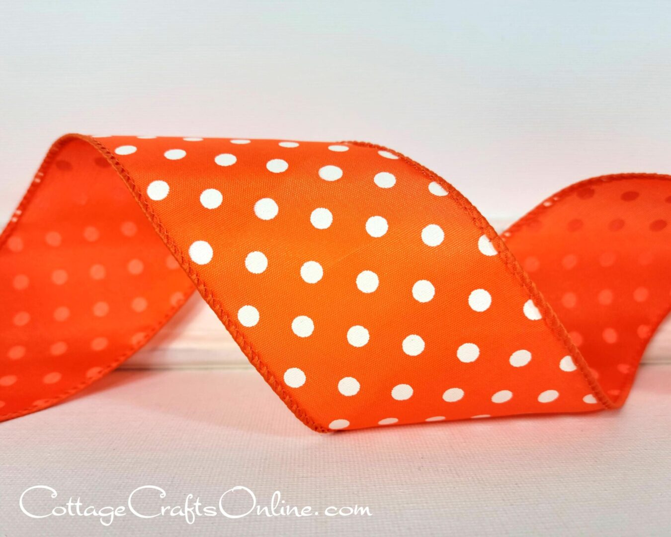 Small white dots on bright orange 2.5" wide wired ribbon from the Etsy shop of Cottage Crafts Online.