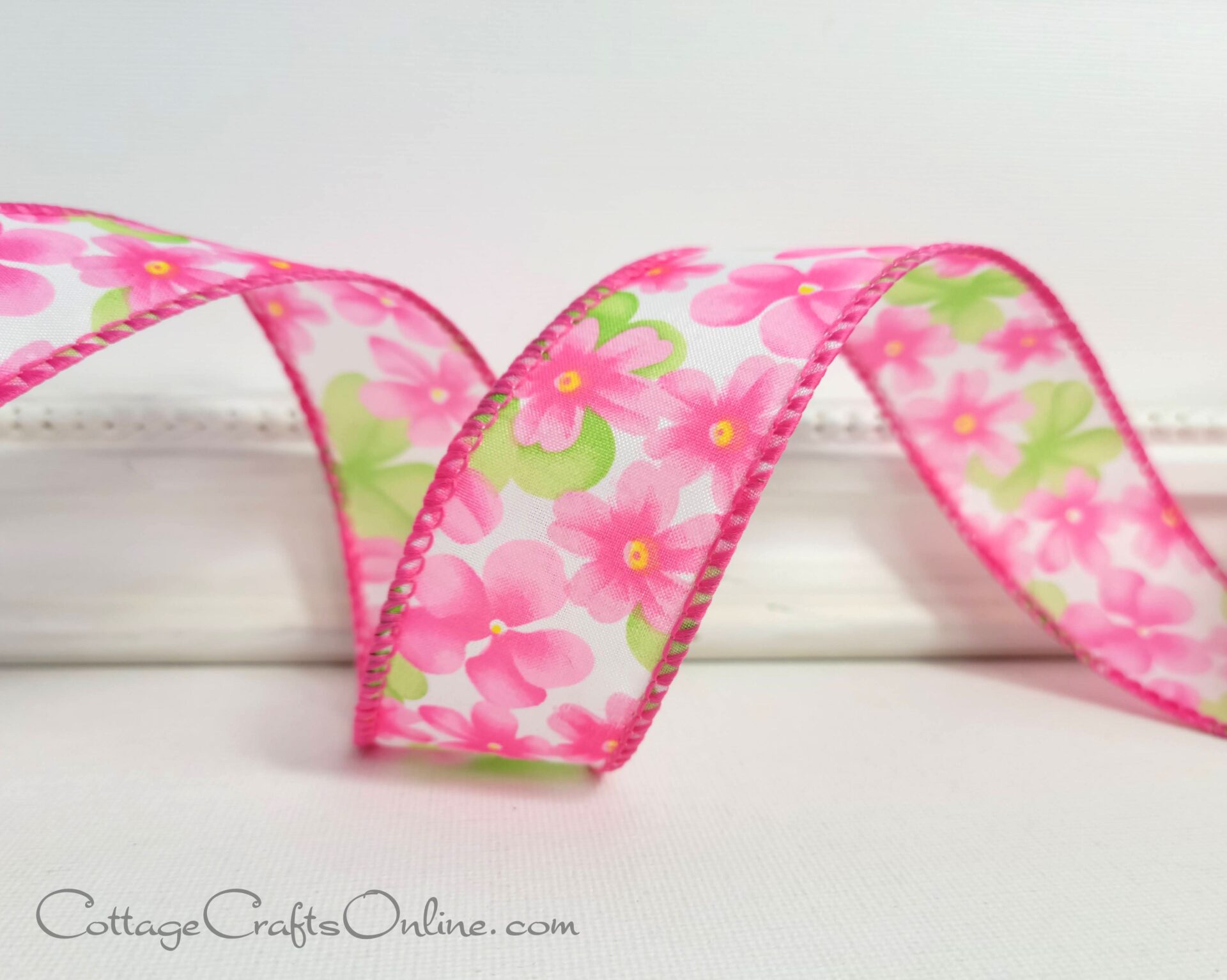 a pink and green ribbon with flowers on it.