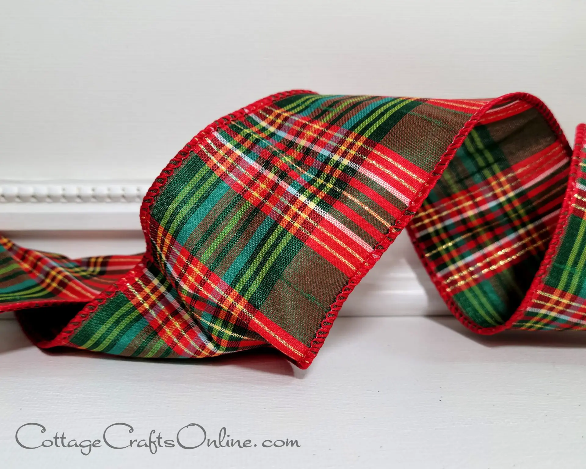 A new fall ribbon with a red and green plaid pattern is displayed on a white shelf.