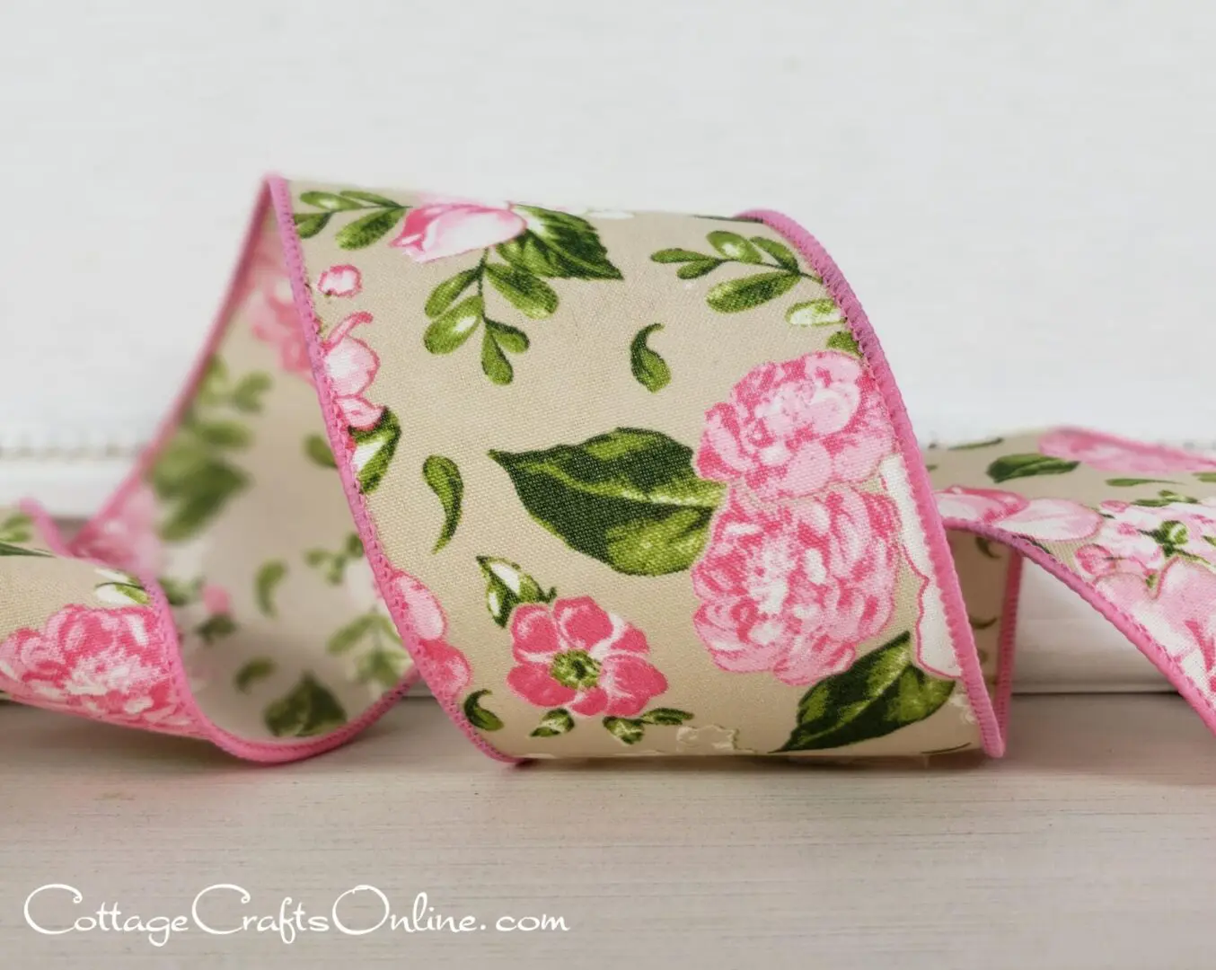 a pink and green floral ribbon on a wooden surface.
