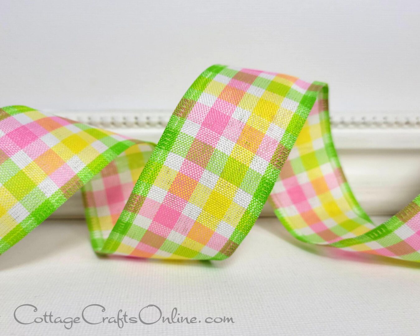 a pink and yellow gingham ribbon on a white table.
