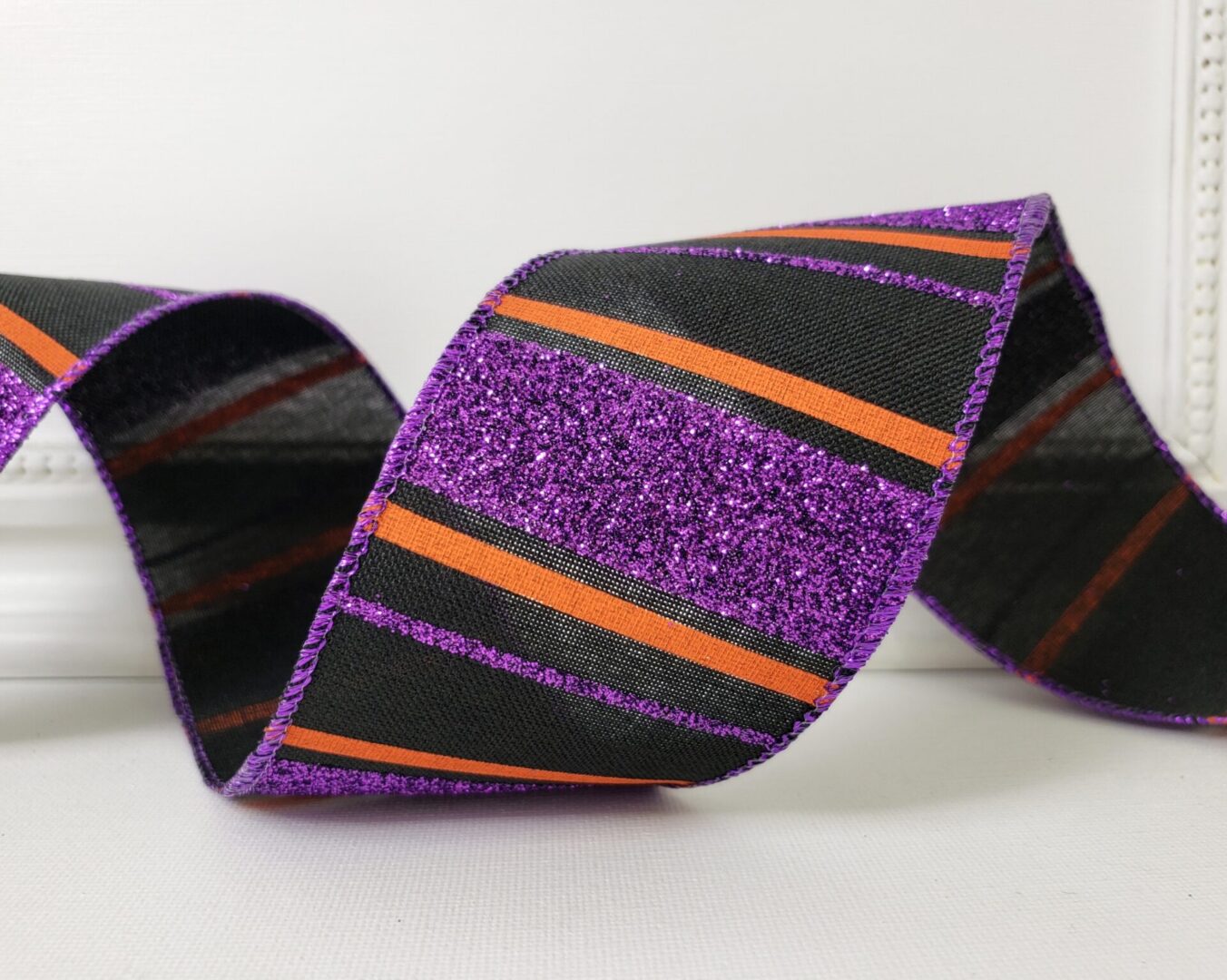 Purple glitter stripes on black mesh with orange accents 2.5" wide wired ribbon from the Etsy shop of Cottage Crafts Online.