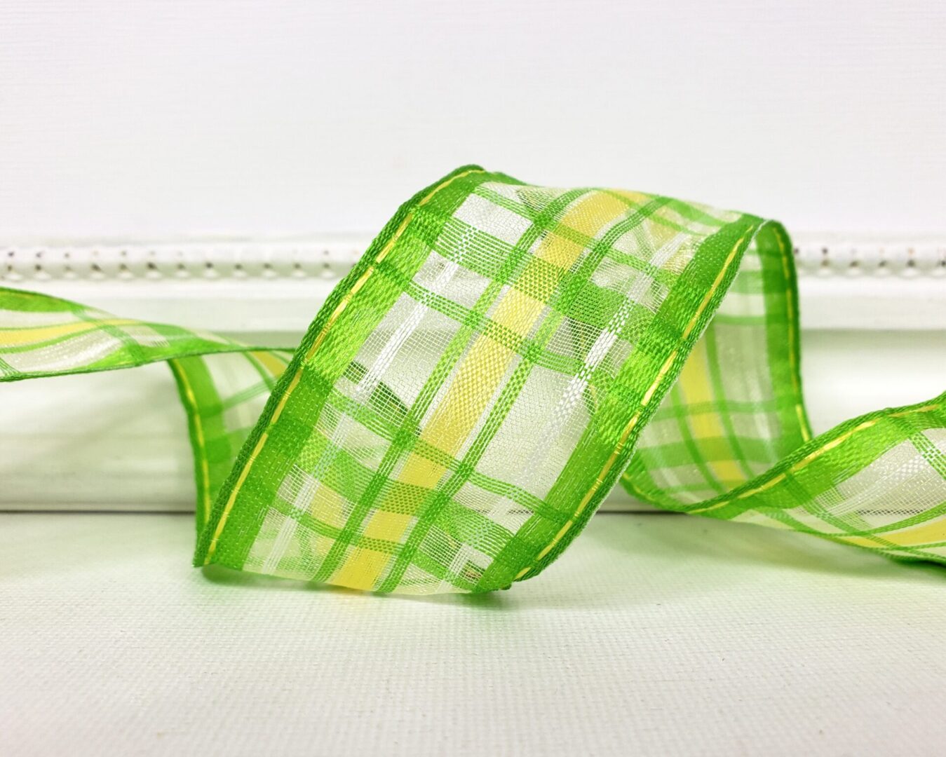 A transluscent semi sheer wired edge ribbon with a green and yellow plaid pattern