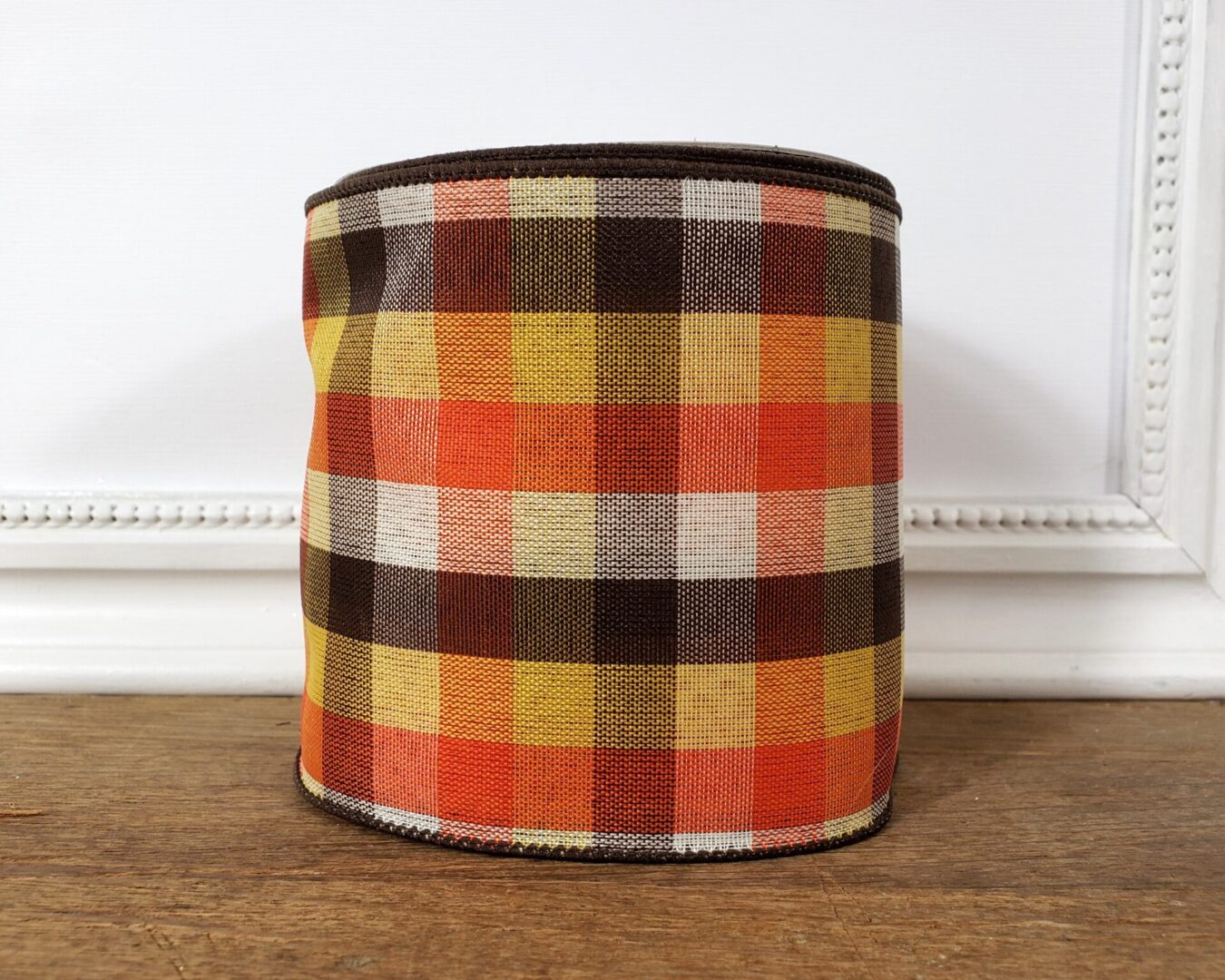 A brown, orange and yellow plaid container sitting on top of a wooden floor.