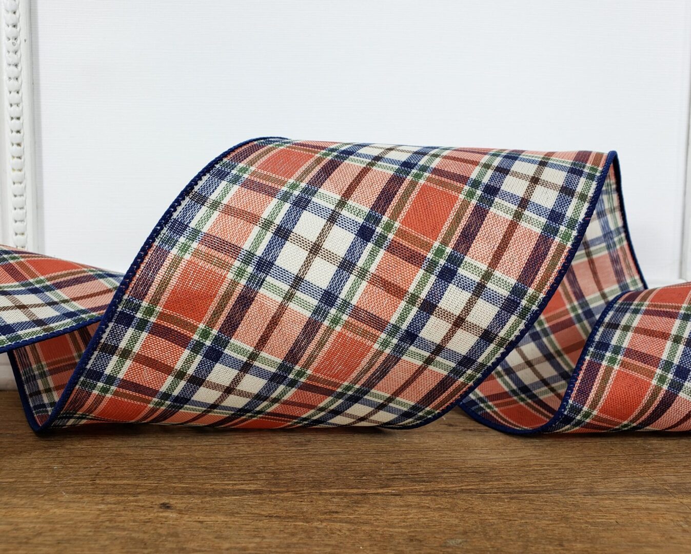 an orange and blue plaid ribbon on a wooden table.