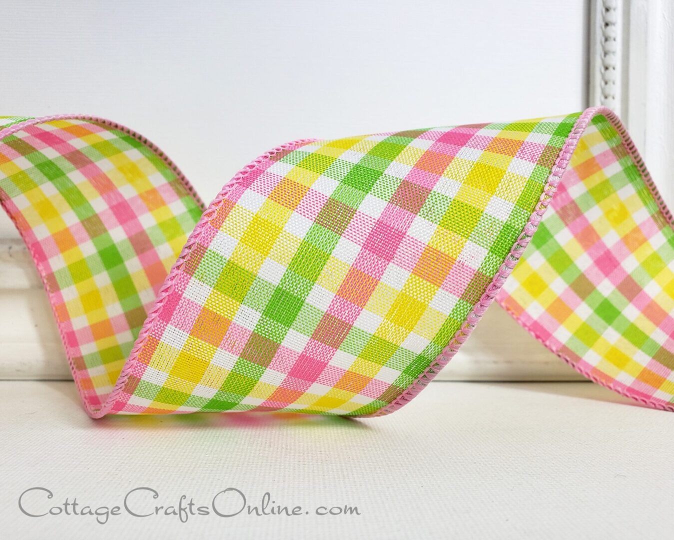 a pink and yellow gingham ribbon on a white table.
