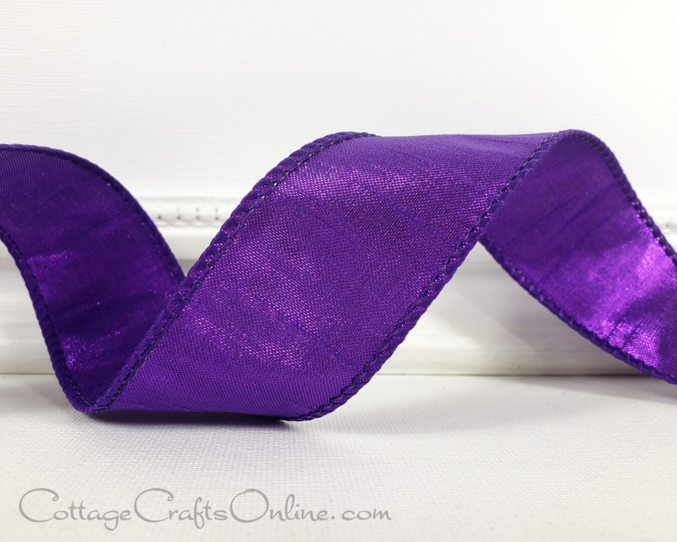 a purple satin ribbon on a white surface.