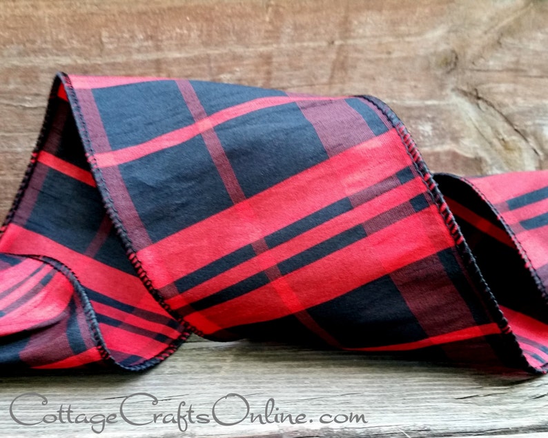 A red and black plaid ribbon is sitting on top of a wooden table.