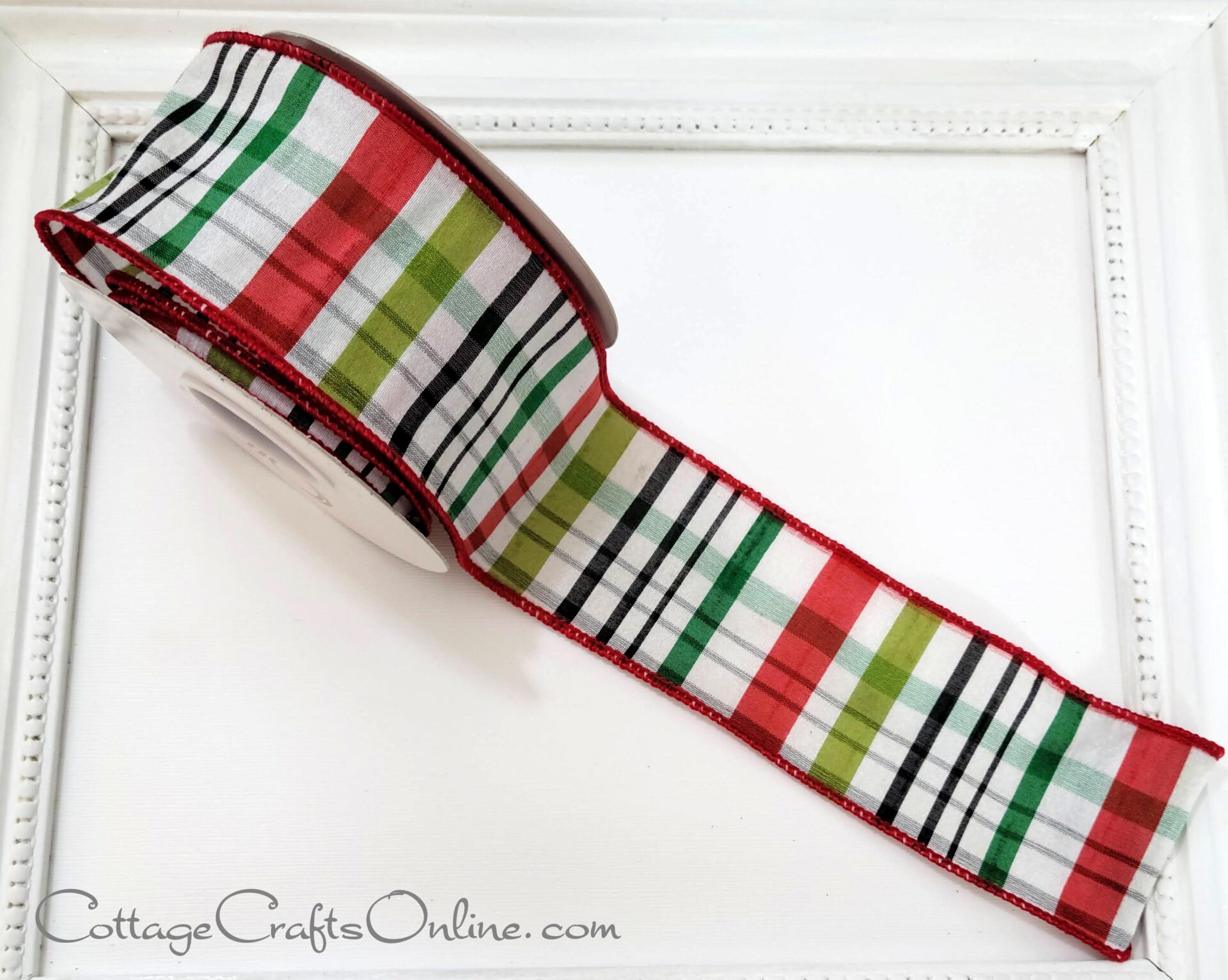 A new plaid ribbon in red, green, and black decorates a white frame.