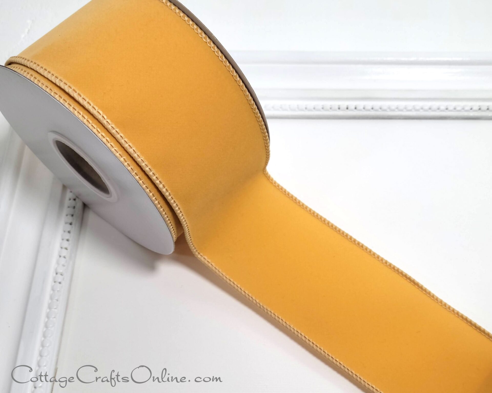 a roll of yellow satin ribbon adorned on a white frame for the new holiday season of 2022.