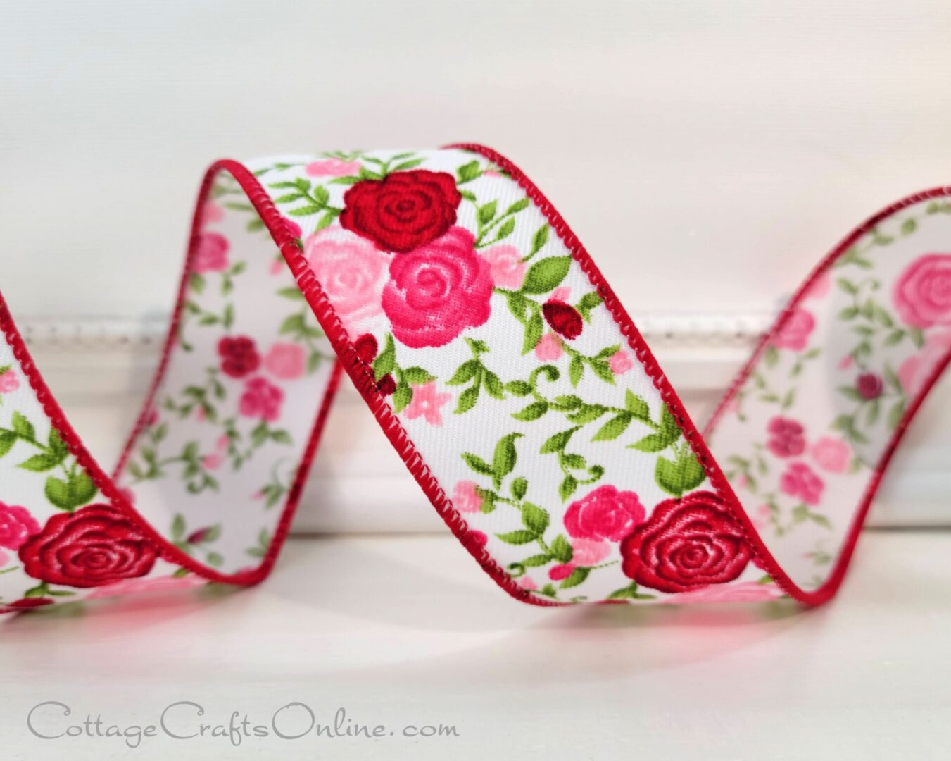 A close up of a ribbon with red and pink roses on it