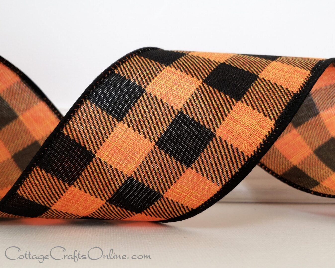 an orange and black plaid ribbon on a white surface.