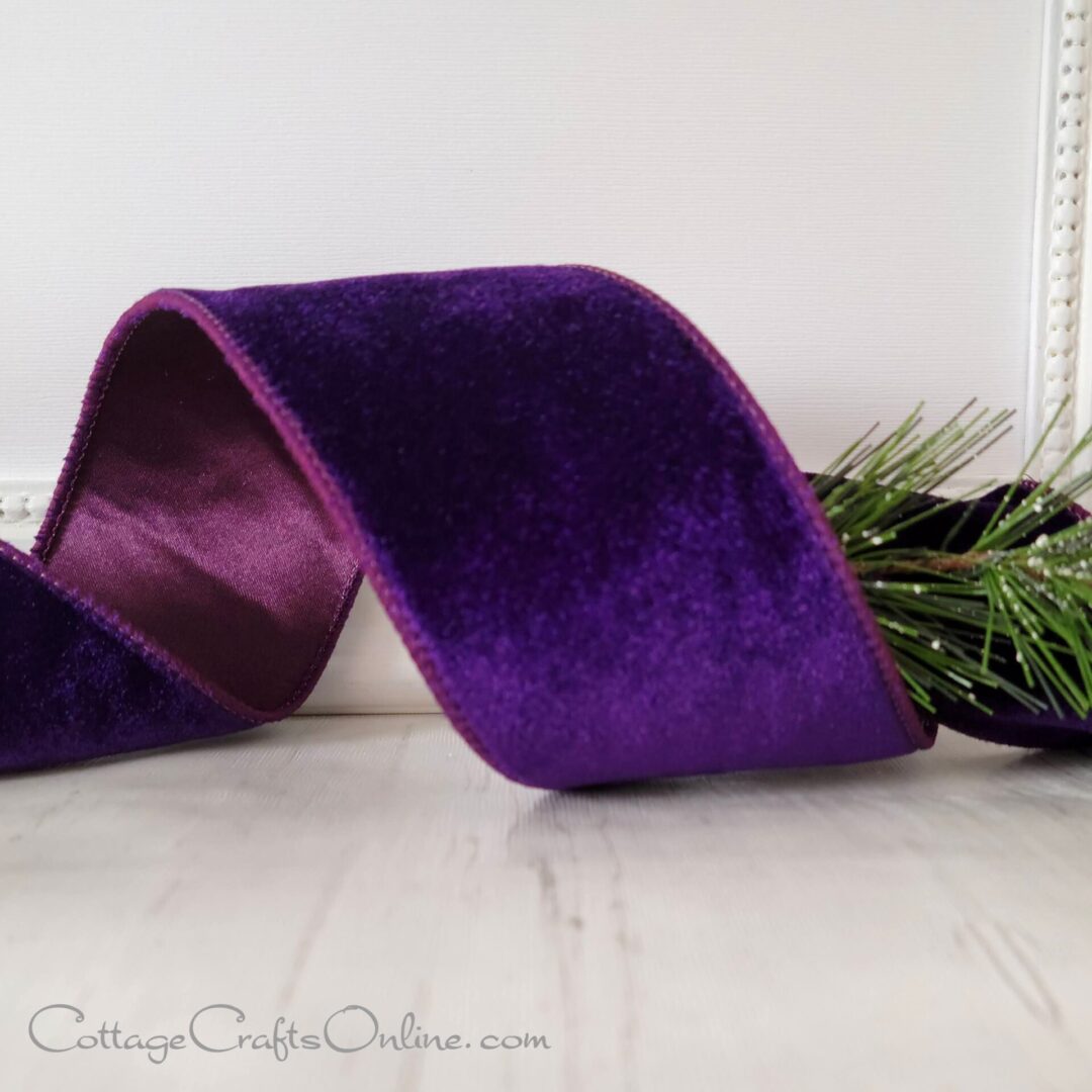 A purple velvet ribbon sitting on top of a wooden table.