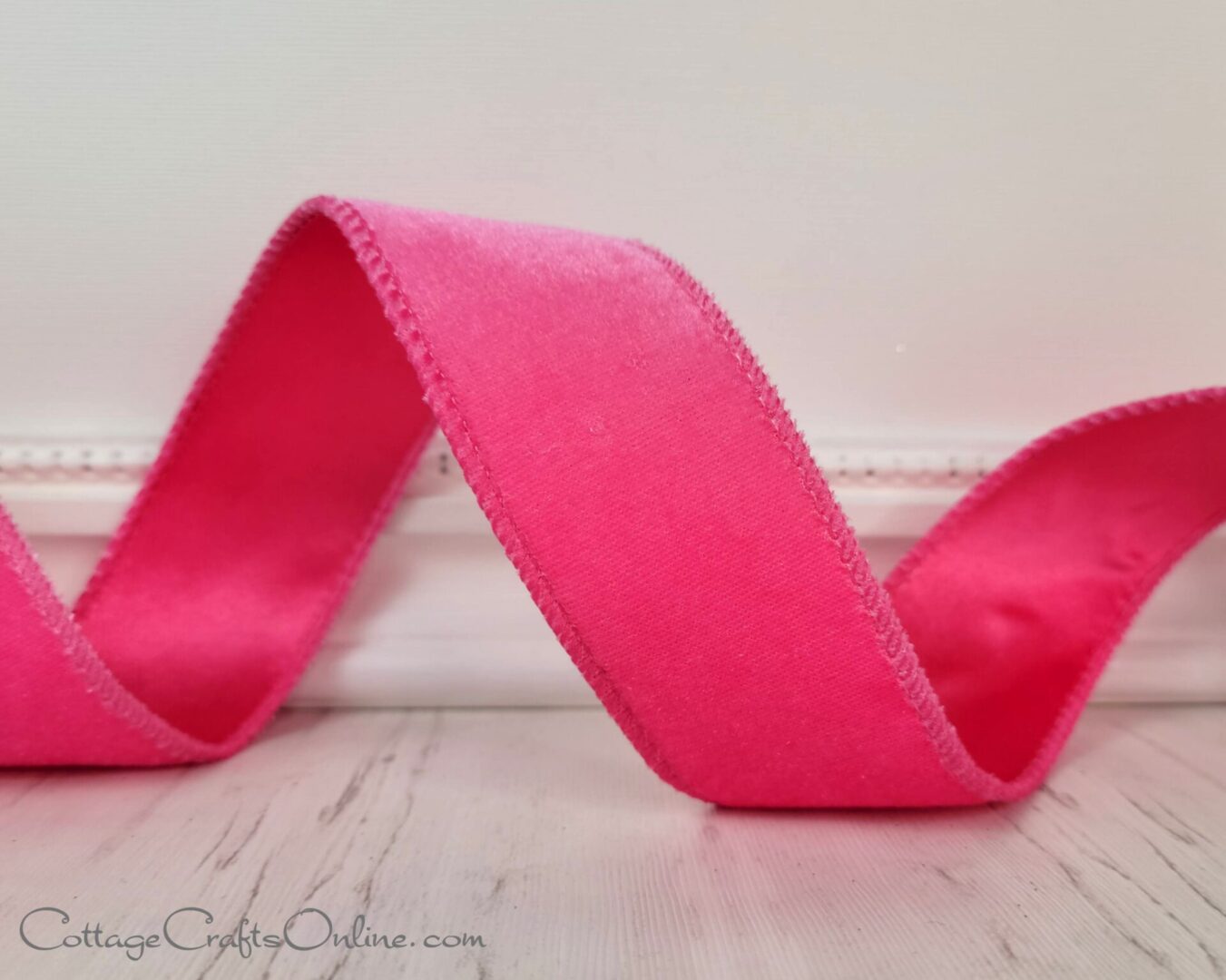 A pink ribbon is curled up on the floor.