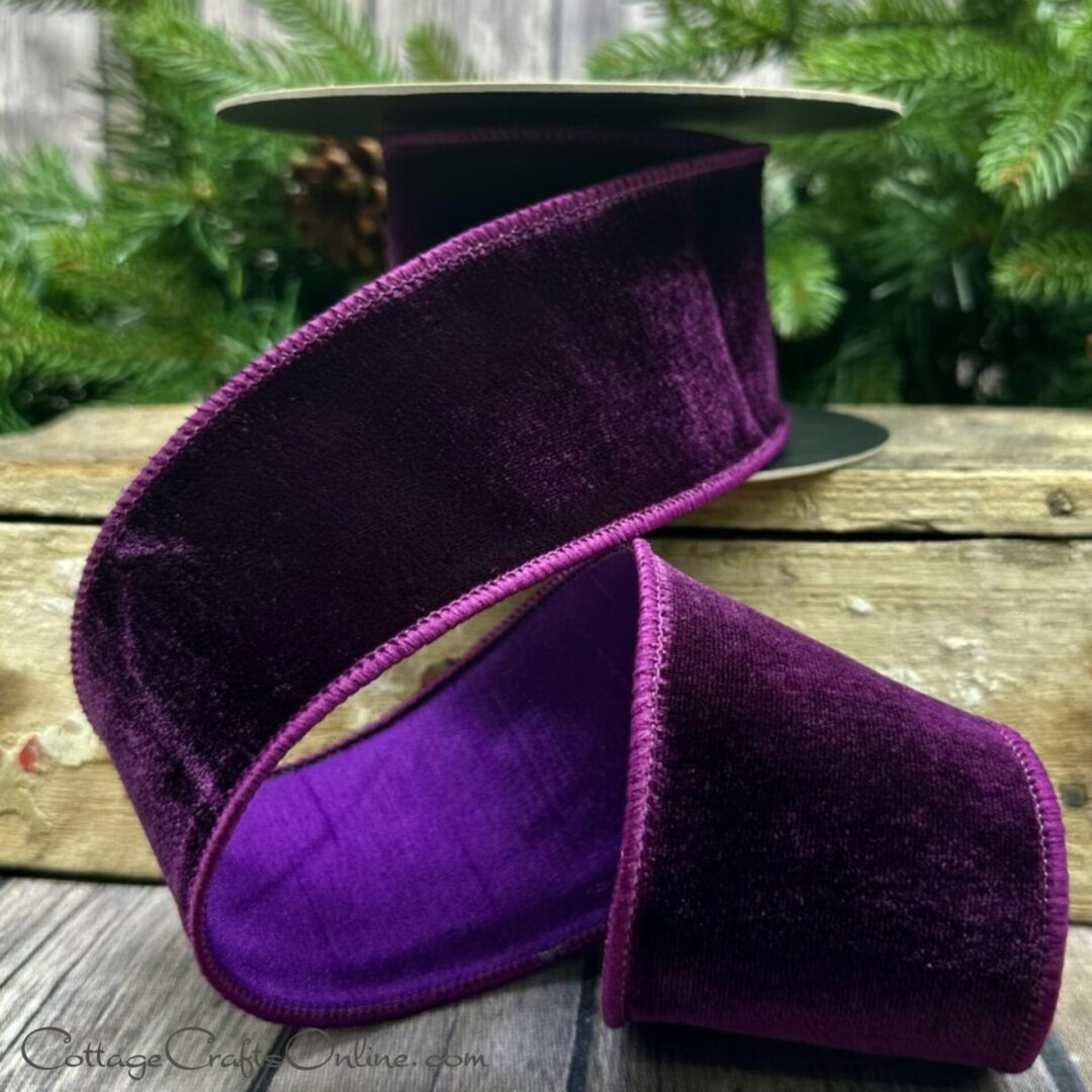 A purple velvet ribbon is sitting on top of a wooden table.